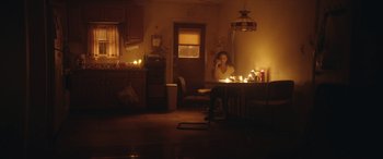 Movie still from “On the Come Up” (2022), directed by Sanaa Lathan – A woman sitting at a table in a dimly - lit room; Wide shot, Low angle