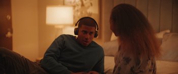 Movie still from “On the Come Up” (2022), directed by Sanaa Lathan – A man wearing headphones talking to a woman in a bedroom; Medium shot, Over the shoulder angle