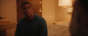 Movie still from “On the Come Up” (2022), directed by Sanaa Lathan – A man sitting on top of a bed in a bedroom; Close Up shot, Over the shoulder angle