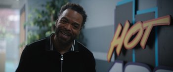 Movie still from “On the Come Up” (2022), directed by Sanaa Lathan – A man smiling for the camera in front of a mural; Close Up shot, Over the shoulder angle