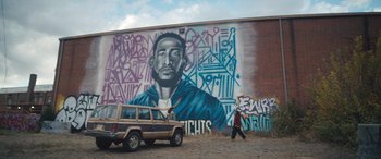 Movie still from “On the Come Up” (2022), directed by Sanaa Lathan – A man walking past a mural of a black man; Medium shot, Low angle