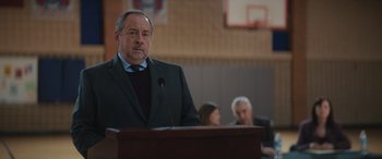 Movie still from “On the Come Up” (2022), directed by Sanaa Lathan – A man standing at a podium in front of a microphone; Close Up shot, Over the shoulder angle