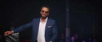 Movie still from “On the Come Up” (2022), directed by Sanaa Lathan – A man in a blue suit and white shirt; Medium shot, Over the shoulder angle