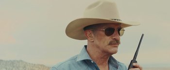 Movie still from “One Ranger” (2023), directed by Jesse V. Johnson – An older man wearing a cowboy hat and sunglasses; Close Up shot, Low angle