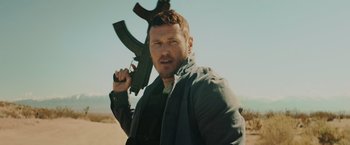 Movie still from “One Ranger” (2023), directed by Jesse V. Johnson – A man holding an ak - 4 7 rifle in his hand; Close Up shot, Low angle
