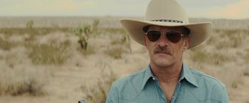 Movie still from “One Ranger” (2023), directed by Jesse V. Johnson – A man wearing a cowboy hat and sun glasses; Close Up shot, Over the shoulder angle