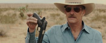 Movie still from “One Ranger” (2023), directed by Jesse V. Johnson – A man in a cowboy hat holding a gun; Close Up shot, Over the shoulder angle