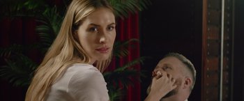 Movie still from “One Ranger” (2023), directed by Jesse V. Johnson – A woman is putting lipstick on a man's face; Close Up shot, Over the shoulder angle