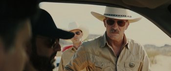 Movie still from “One Ranger” (2023), directed by Jesse V. Johnson – A group of men standing next to each other in a car; Close Up shot, Over the shoulder angle