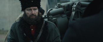 Movie still from “One Ranger” (2023), directed by Jesse V. Johnson – A man with a long beard wearing a fur hat; Close Up shot, Over the shoulder angle