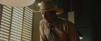 Movie still from “One Ranger” (2023), directed by Jesse V. Johnson – A man wearing a cowboy hat and a tie; Medium shot, Over the shoulder angle