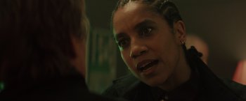 Movie still from “One Ranger” (2023), directed by Jesse V. Johnson – A woman is talking to another person in a room; Close Up shot, Over the shoulder angle