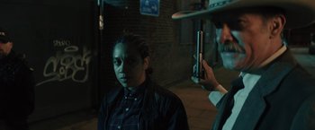 Movie still from “One Ranger” (2023), directed by Jesse V. Johnson – A man taking a picture of a woman with a cell phone; Medium shot, Over the shoulder angle