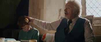 Movie still from “One Ranger” (2023), directed by Jesse V. Johnson – An older man wearing a vest and a tie; Medium shot, Over the shoulder angle