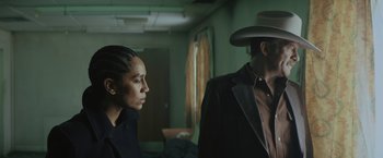 Movie still from “One Ranger” (2023), directed by Jesse V. Johnson – A man and a woman standing next to each other in a room; Medium shot, Low angle