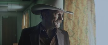 Movie still from “One Ranger” (2023), directed by Jesse V. Johnson – A man wearing a cowboy hat looking out of a window; Close Up shot, Low angle