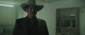 Movie still from “One Ranger” (2023), directed by Jesse V. Johnson – A man in a hat and a brown jacket; Medium shot, Over the shoulder angle