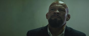 Movie still from “One Ranger” (2023), directed by Jesse V. Johnson – A man in a suit and beard looking up; Close Up shot, Low angle