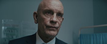 Movie still from “One Ranger” (2023), directed by Jesse V. Johnson – An older man wearing a suit and a tie; Close Up shot, Low angle