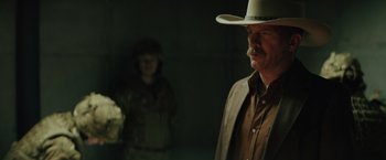Movie still from “One Ranger” (2023), directed by Jesse V. Johnson – A man in a cowboy hat standing next to a woman; Medium shot, Over the shoulder angle
