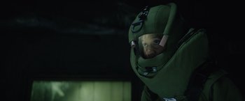 Movie still from “One Ranger” (2023), directed by Jesse V. Johnson – A person in a green suit and helmet; Close Up shot, Over the shoulder angle