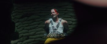 Movie still from “One Ranger” (2023), directed by Jesse V. Johnson – A man in a white tank top and yellow pants; Medium shot, High angle