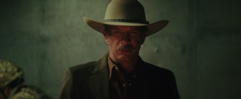 Movie still from “One Ranger” (2023), directed by Jesse V. Johnson – A man in a suit and a cowboy hat; Close Up shot, Low angle