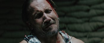 Movie still from “One Ranger” (2023), directed by Jesse V. Johnson – A person with blood on his face; Close Up shot, High angle