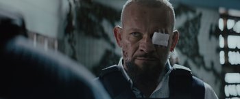 Movie still from “One Ranger” (2023), directed by Jesse V. Johnson – A person with a bandage on his eye; Close Up shot, Over the shoulder angle
