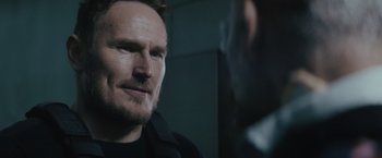 Movie still from “One Ranger” (2023), directed by Jesse V. Johnson – A person wearing a black jacket; Close Up shot, Over the shoulder angle