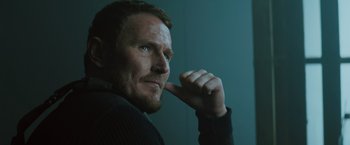 Movie still from “One Ranger” (2023), directed by Jesse V. Johnson – A person holding his hand up to his face; Close Up shot, Low angle