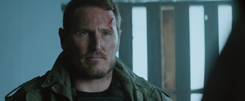 Movie still from “One Ranger” (2023), directed by Jesse V. Johnson – A person with a scar on his face; Close Up shot, Over the shoulder angle