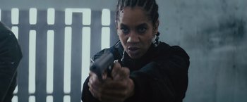 Movie still from “One Ranger” (2023), directed by Jesse V. Johnson – A woman holding a gun in her hand; Close Up shot, Low angle