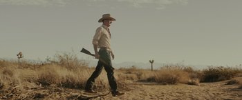 Movie still from “One Ranger” (2023), directed by Jesse V. Johnson – A man in a cowboy hat walking through the desert; Wide shot, Low angle