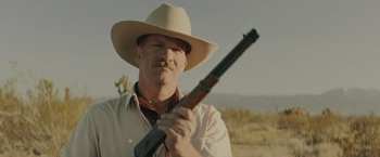 Movie still from “One Ranger” (2023), directed by Jesse V. Johnson – A man holding a rifle while wearing a cowboy hat; Close Up shot, Low angle