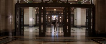Movie still from “Operation Fortune: Ruse de Guerre” (2023), directed by Guy Ritchie – A man walking through a hallway in a building; Wide shot, Low angle
