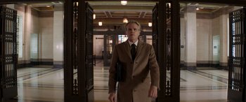 Movie still from “Operation Fortune: Ruse de Guerre” (2023), directed by Guy Ritchie – A man in a suit and tie standing in a hallway; Medium shot, Low angle