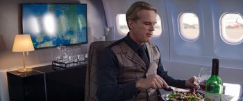 Movie still from “Operation Fortune: Ruse de Guerre” (2023), directed by Guy Ritchie – A man sitting at a table with a plate of food; Medium shot, Over the shoulder angle