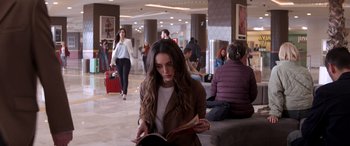 Movie still from “Operation Fortune: Ruse de Guerre” (2023), directed by Guy Ritchie – A woman is reading a book in a lobby; Medium shot, Over the shoulder angle