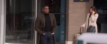 Movie still from “Operation Fortune: Ruse de Guerre” (2023), directed by Guy Ritchie – A man in a black shirt and a brown coat; Medium shot, Low angle