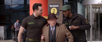 Movie still from “Operation Fortune: Ruse de Guerre” (2023), directed by Guy Ritchie – A group of men standing next to each other near a building; Medium shot, Over the shoulder angle