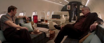 Movie still from “Operation Fortune: Ruse de Guerre” (2023), directed by Guy Ritchie – A person sitting on a couch in a room with a lot of furniture; Wide shot, High angle