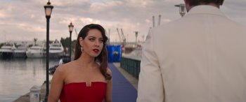 Movie still from “Operation Fortune: Ruse de Guerre” (2023), directed by Guy Ritchie – A woman in a red dress standing next to a man in a white suit; Close Up shot, Over the shoulder angle