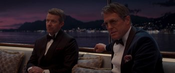 Movie still from “Operation Fortune: Ruse de Guerre” (2023), directed by Guy Ritchie – A couple of men sitting next to each other on top of a boat; Medium shot, Over the shoulder angle