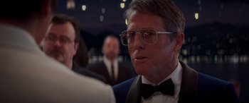 Movie still from “Operation Fortune: Ruse de Guerre” (2023), directed by Guy Ritchie – A person wearing glasses and a bow tie; Close Up shot, Over the shoulder angle