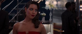 Movie still from “Operation Fortune: Ruse de Guerre” (2023), directed by Guy Ritchie – A woman in a strapless red dress looking to her left; Close Up shot, Over the shoulder angle