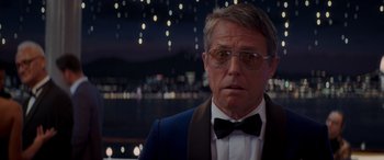 Movie still from “Operation Fortune: Ruse de Guerre” (2023), directed by Guy Ritchie – A person wearing a suit and bow tie; Close Up shot, Over the shoulder angle
