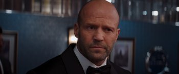 Movie still from “Operation Fortune: Ruse de Guerre” (2023), directed by Guy Ritchie – A bald man in a black suit and bow tie; Close Up shot, Low angle