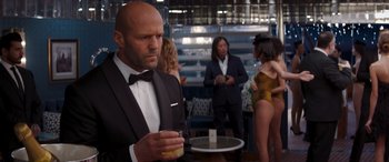 Movie still from “Operation Fortune: Ruse de Guerre” (2023), directed by Guy Ritchie – A man in a tuxedo holding a drink in his hand; Medium shot, Over the shoulder angle