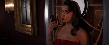 Movie still from “Operation Fortune: Ruse de Guerre” (2023), directed by Guy Ritchie – A woman in a red dress is holding a cell phone; Close Up shot, Over the shoulder angle